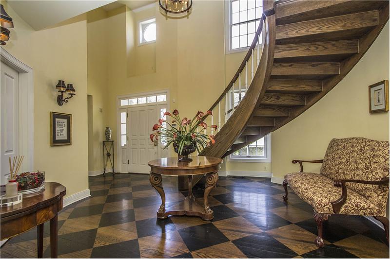 Dramatic 2-story foyer features custom hardwood flooring, designer chandelier, and bridal staircase to the upper level