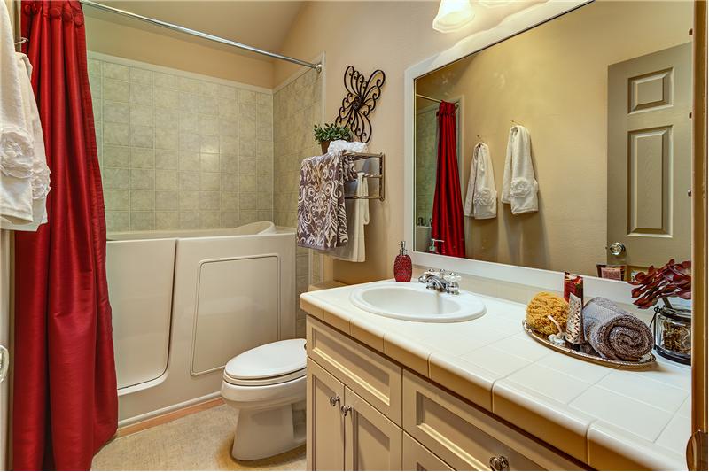 Full Sized Bathroom with Walk-in or Sit Down Shower, Tile Countertops, Vaulted Ceilings and Vinyl Floors.